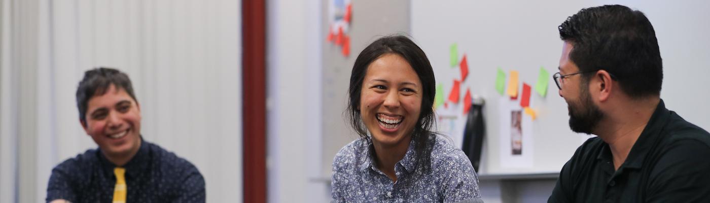Faculty and two students smiling at a table.