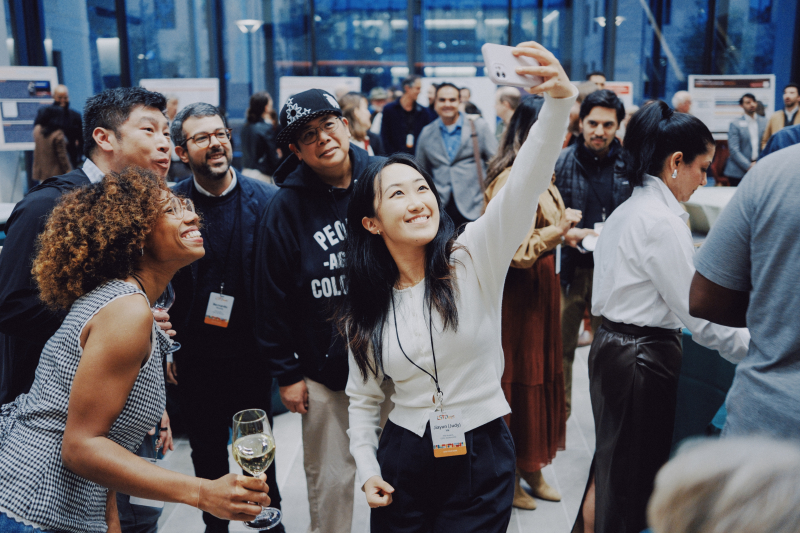 Picture of an alum taking a selfie with several other alumni