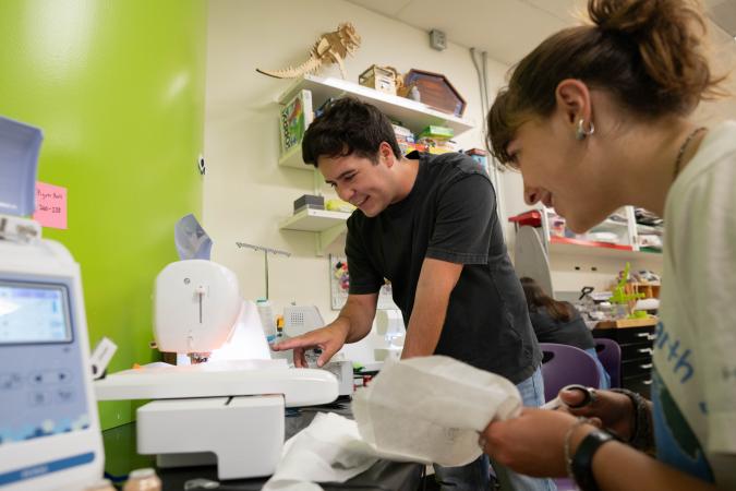 Two students using a piece of equipment in the GSE Makery.