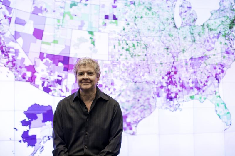 Photo of Sean Reardon in front of U.S. map showing school achievement data