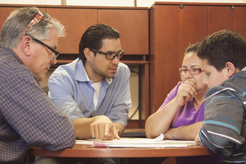 GSE student Efrain Brito, second from left, interprets with Maria Guzman, her son and his teacher, Randy Vail at Pescadero Middle School.