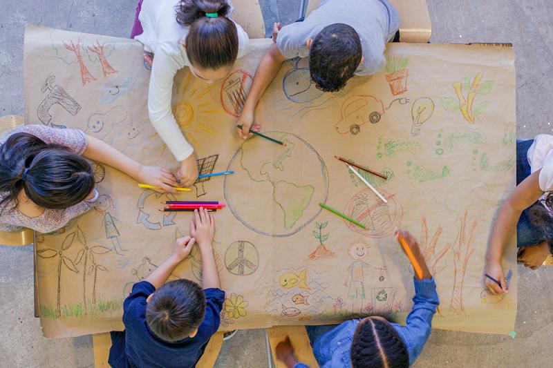 children drawing the earth on a large table