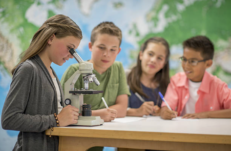 Kids looking at a microscope in class