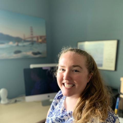 Anna Perry, sitting at a desk, smiling