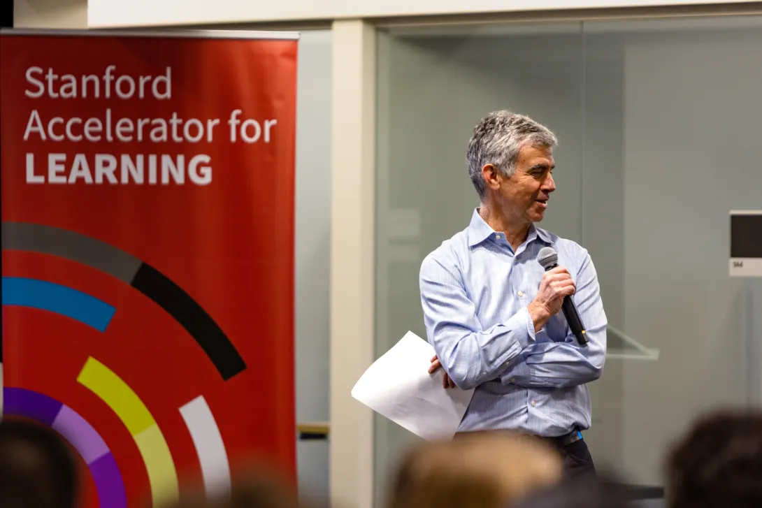 Picture of Dan Schwartz in front of a Stanford Accelerator for Learning banner speaking at an event.
